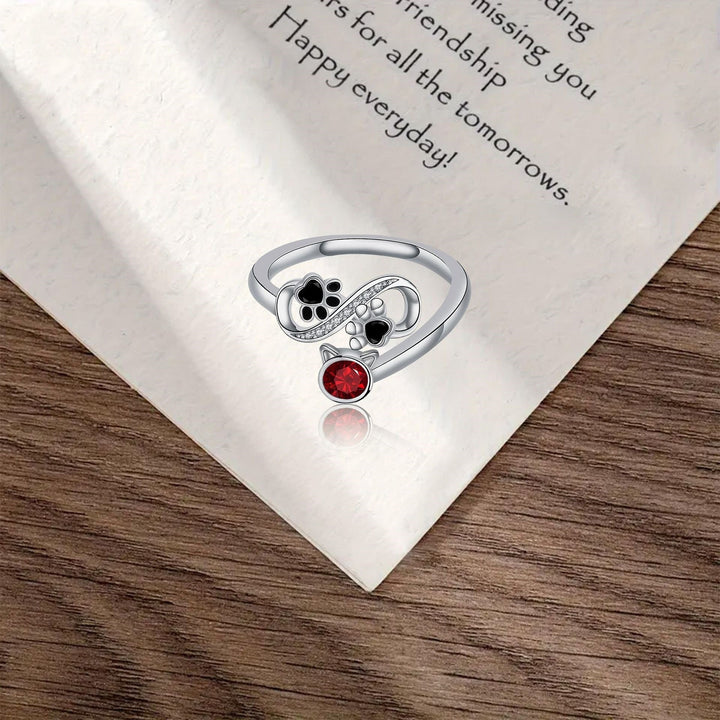 Adjustable ring with black paw print and red gemstones