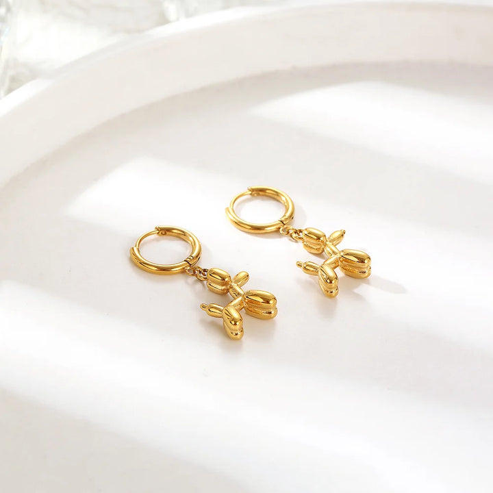 Gold Huggie earrings with a mini balloon-shaped dog pendant