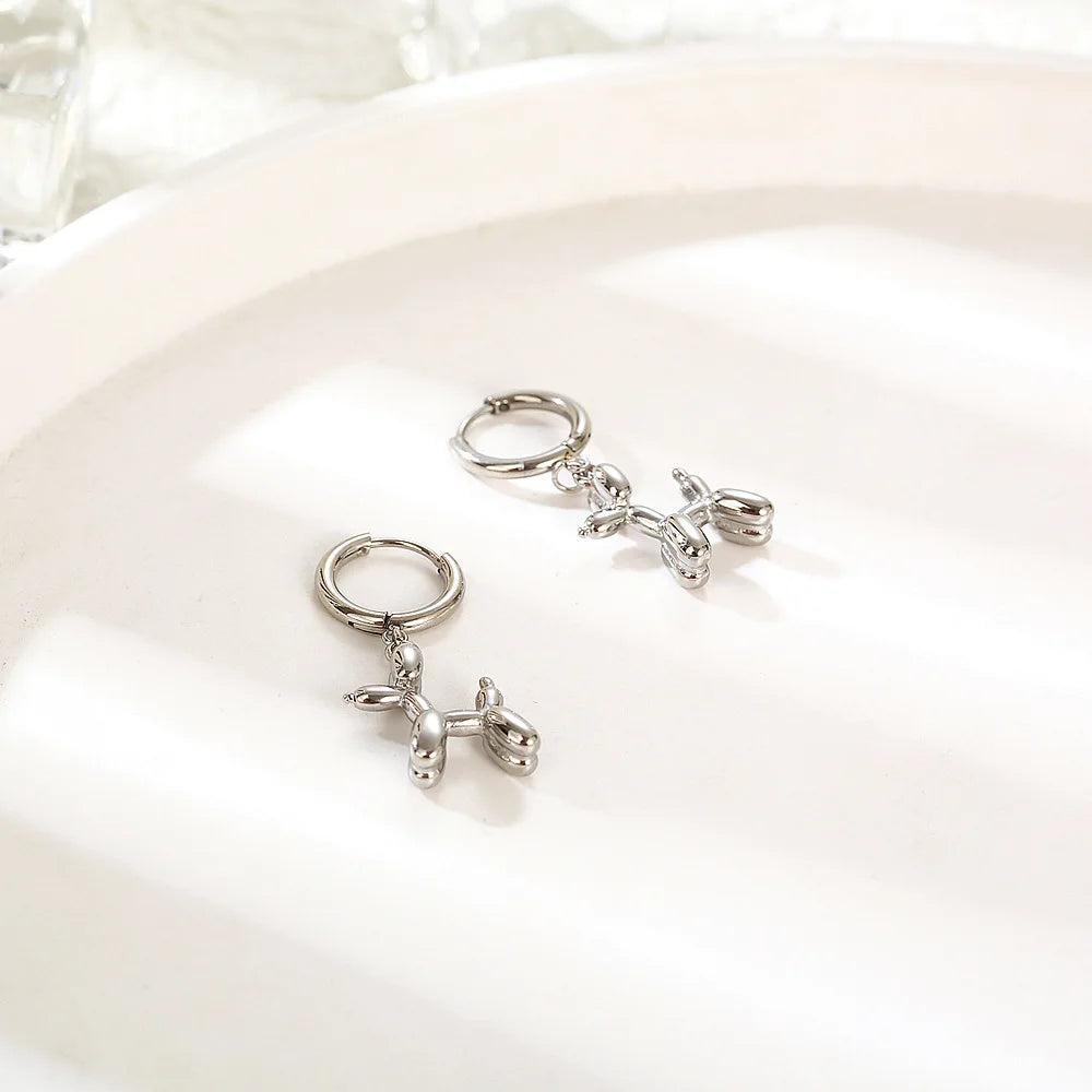 Gold Huggie earrings with a mini balloon-shaped dog pendant