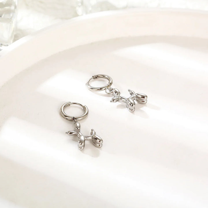 Gold Huggie earrings with a mini balloon-shaped dog pendant